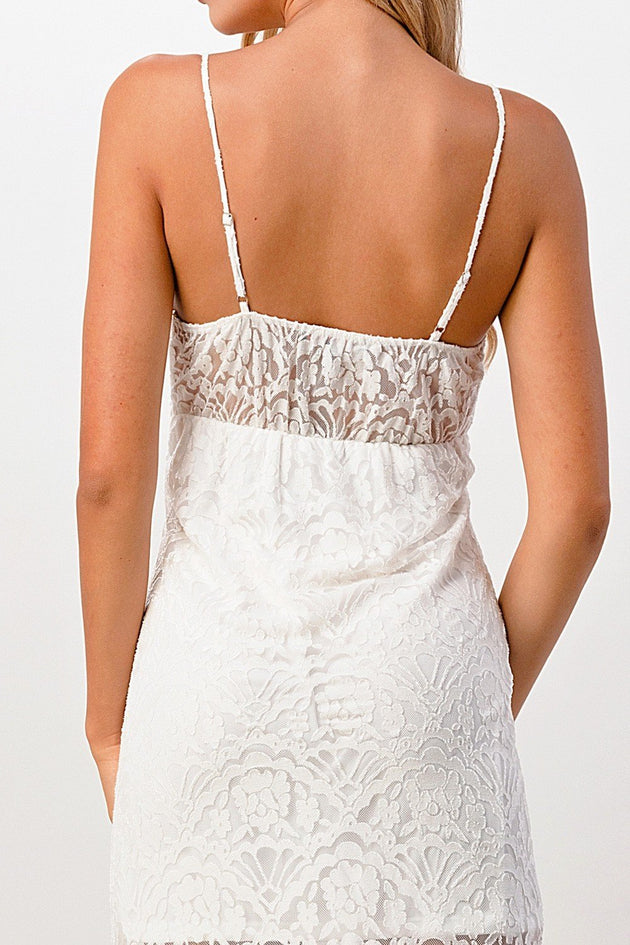 White lace dress with thin straps on a plain background