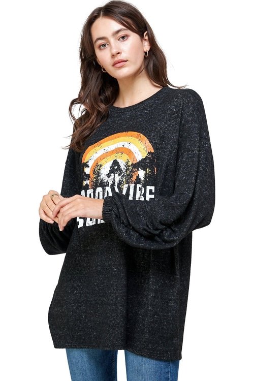 Woman wearing a black oversized sweater with a colorful graphic design on a white background