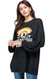 Woman wearing a black oversized sweater with a colorful graphic design on a white background