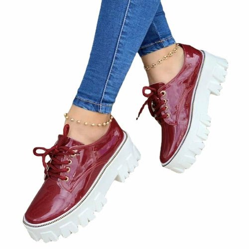 Red platform shoes worn with blue jeans on a white background