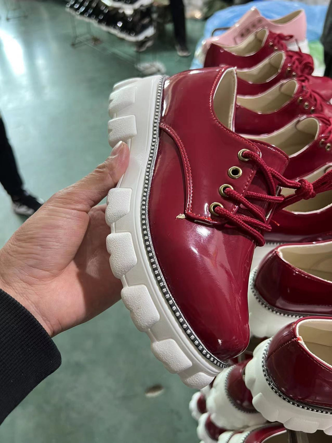 Red shoes with white soles held by a hand on a blurred background
