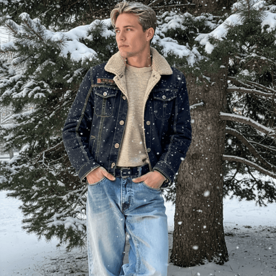 Person wearing a denim jacket with a fur - lined hood in a snowy forest setting