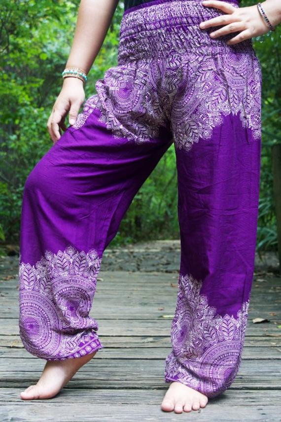 Women’s purple hippie yoga pants worn by a person on a wooden deck with greenery in the background