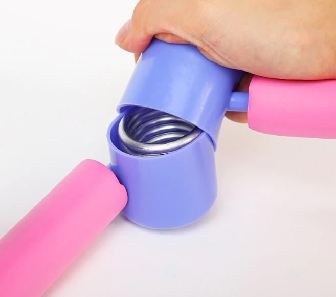Hand holding a pink and purple hand gripper on a white background