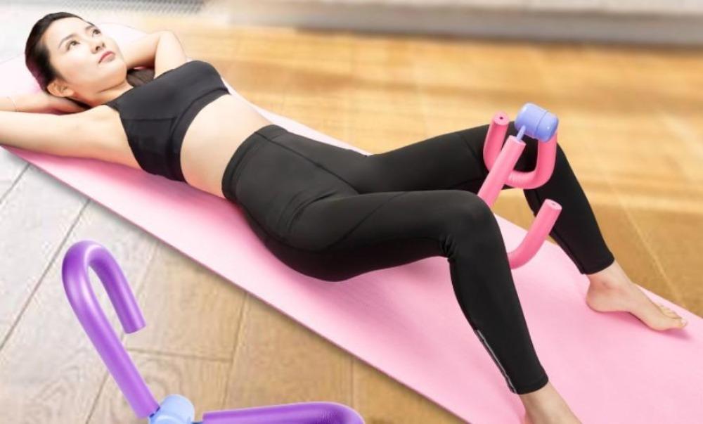 Woman exercising on a pink mat with an exercise tool on a wooden floor.